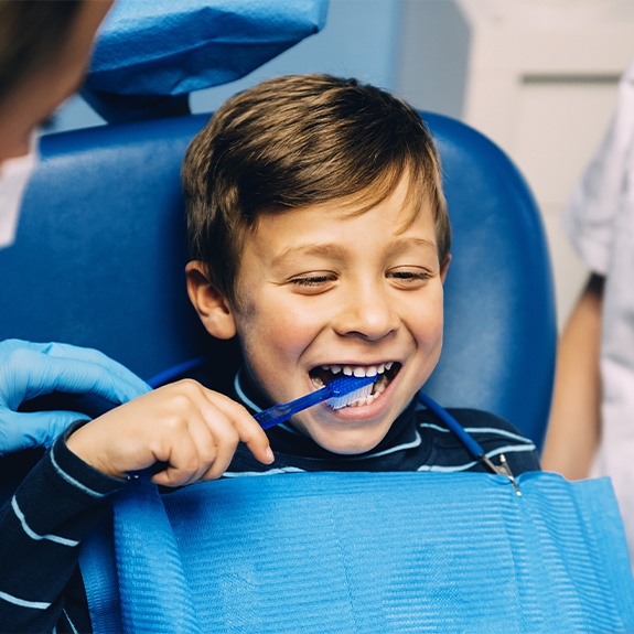 Child at dental office brushing teeth