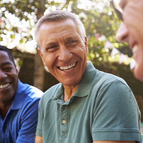 Man laughing with friends after restorative dentistry