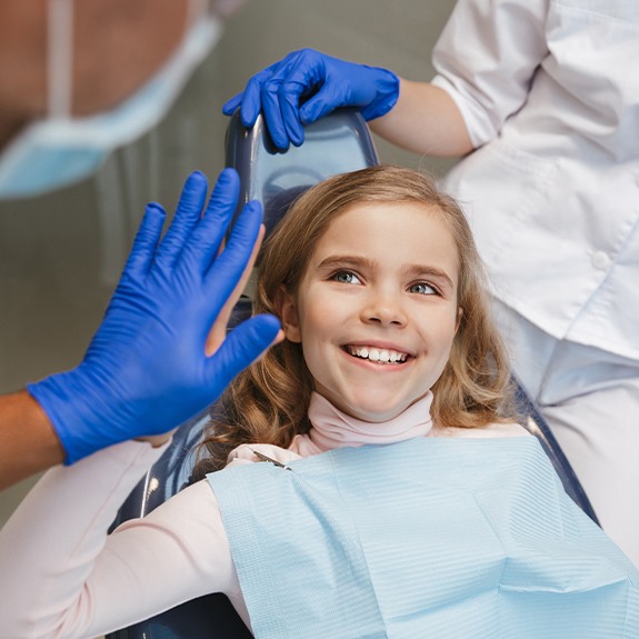 Young girl giving dentist a high five after dental checkup visit