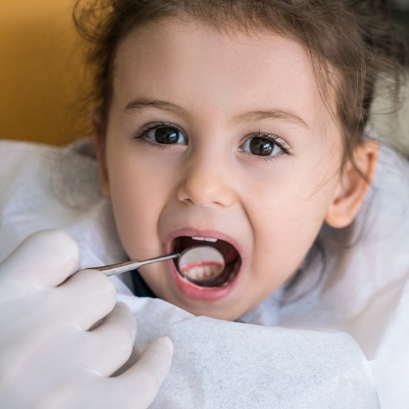 Dentist checking young girl's tooth colored fillings