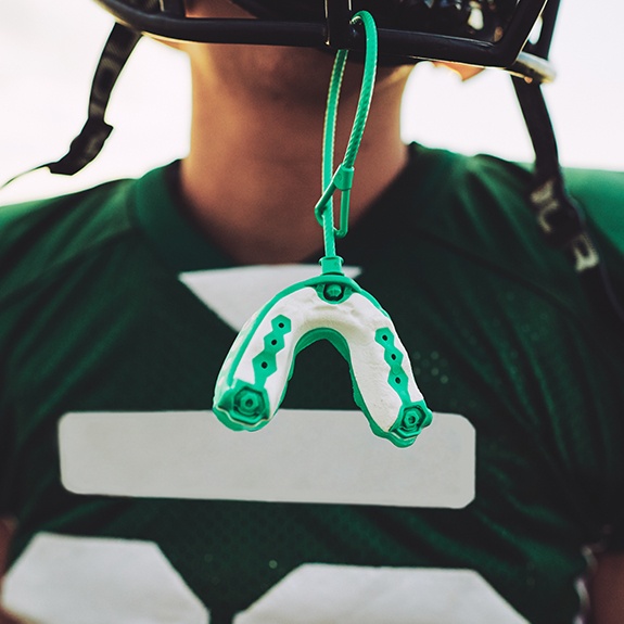 Green athletic mouthguard hanging from football helmet