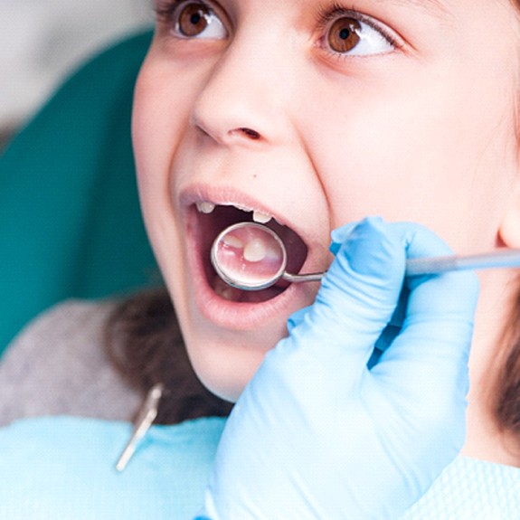 A dentist examines a little girl’s mouth during a regular checkup in Fort Worth