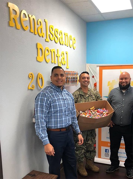 Two dental team members donating candy to military service member