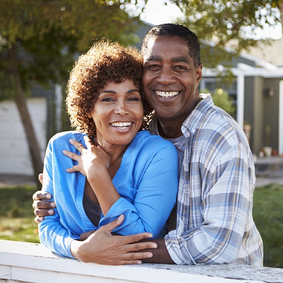 Man and woman smiling after receiving dentures and partials