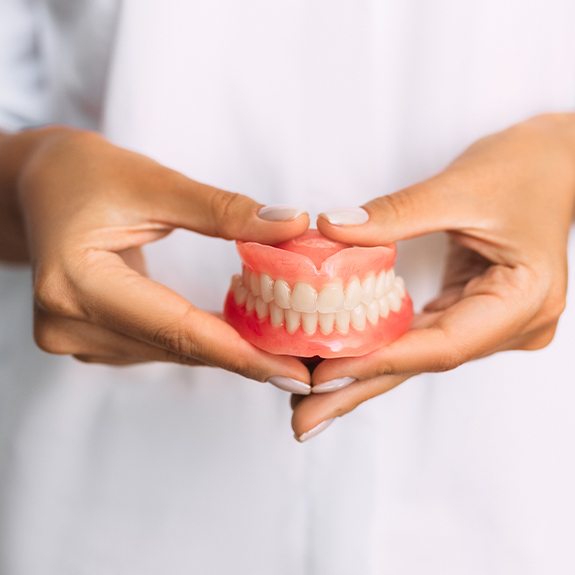 Hand holding a full set of dentures