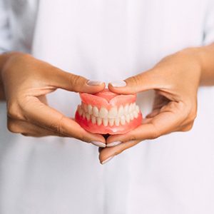 A dentist holding dentures in his hands