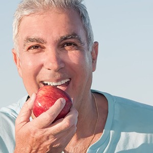 a person with dentures eating an apple