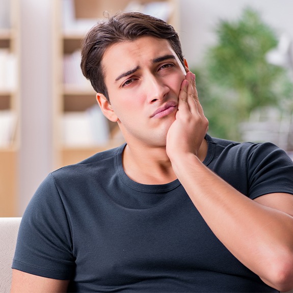 Man in need of tooth extractions holding jaw in pain