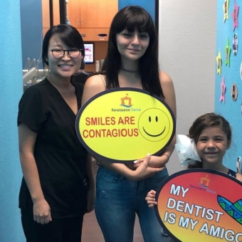 Dental team member with two patients holding signs