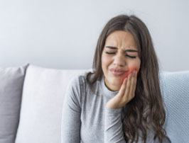 Woman in need of emergency dentistry holding cheek