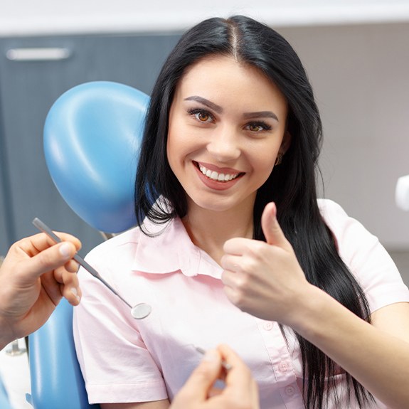 Woman giving thumbs up after visiting the dentist