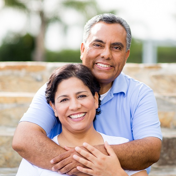 Man and woman smiling after replacing missing teeth