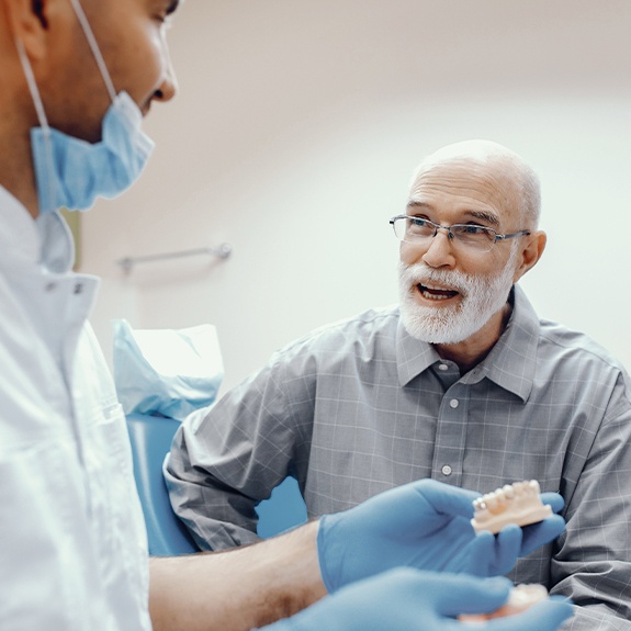 Dentist and patient looking at denture models