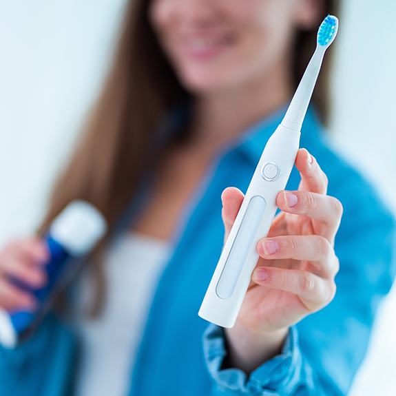 Woman using electric toothbrush for at home oral hygiene