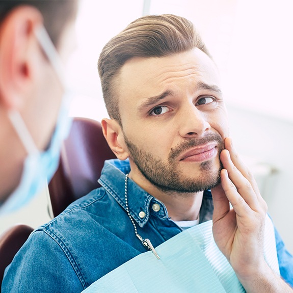 Man in need of root canal therapy holding cheek in pain