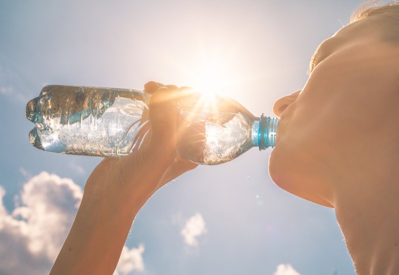 woman drinking water outside during summer