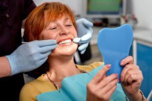 woman looking at dentures in mirror