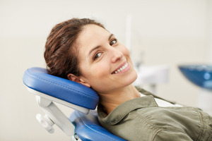 Female dental patient leaning back in chair and smiling